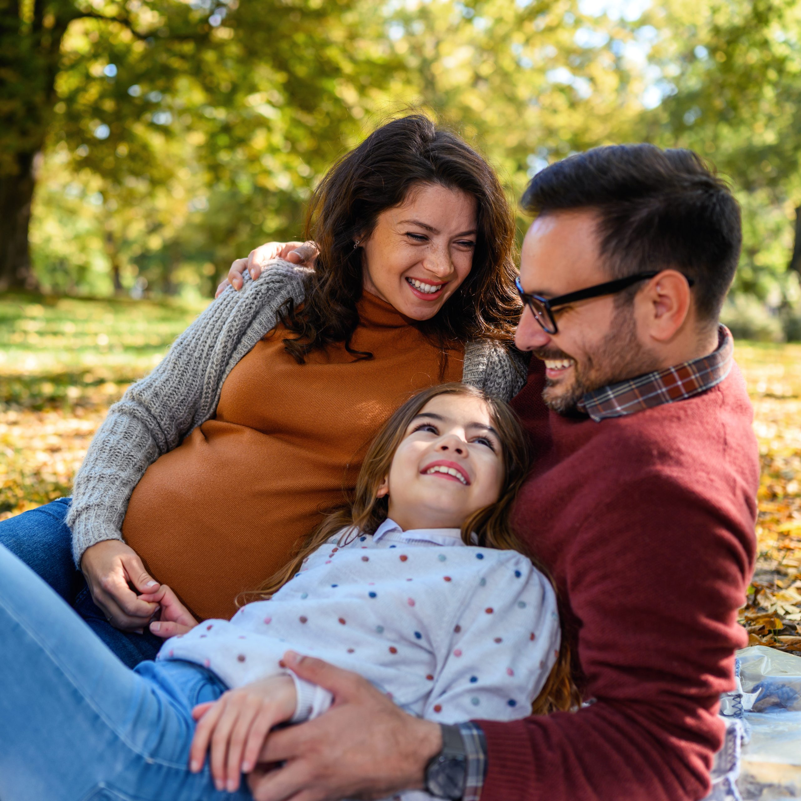 Portrait of a happy caucasian family lying on a picnic blanket in the park.